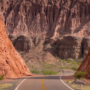 A picturesque road winds through stunning rock formations in Cafayate, Argentina, showcasing nature's beauty.