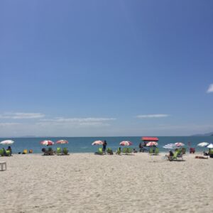 A vibrant beach scene with umbrellas and lounge chairs under a clear blue sky.