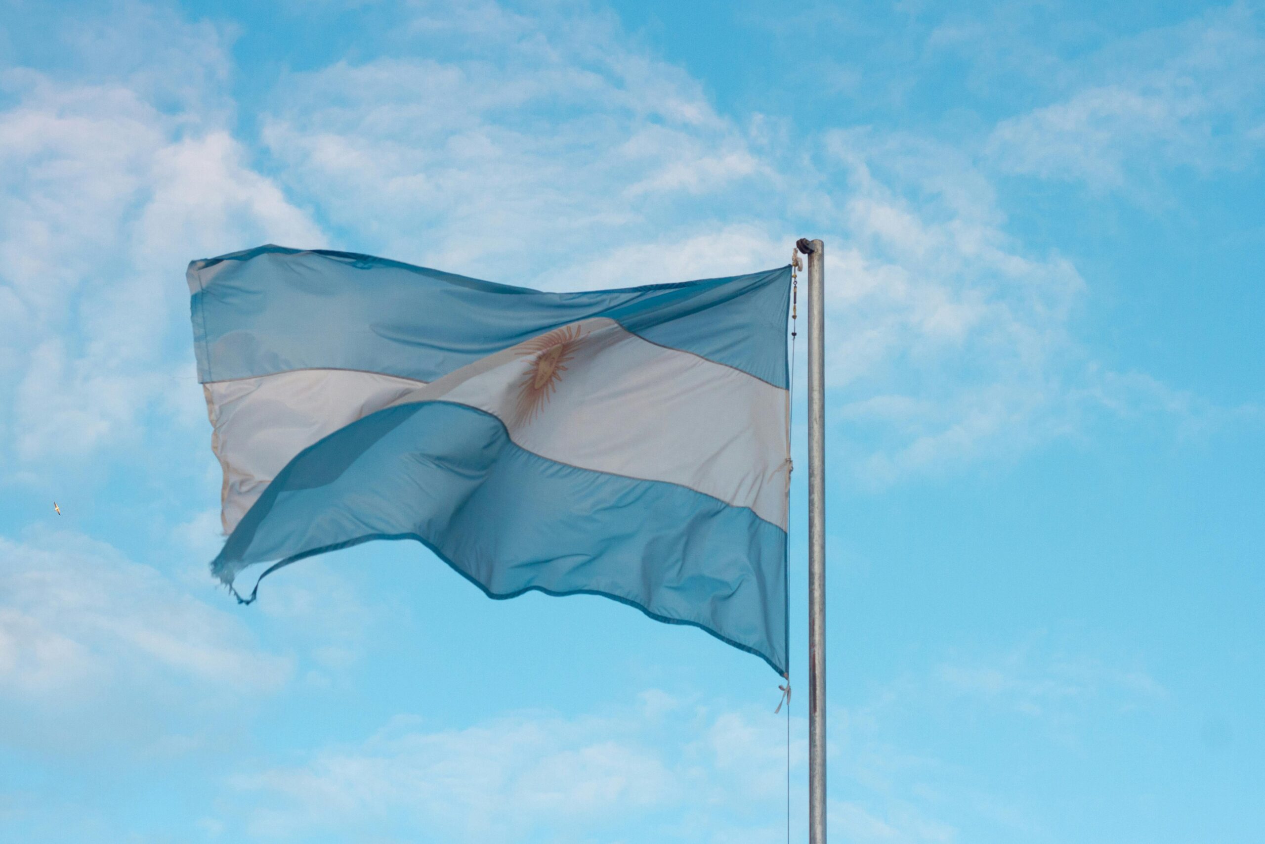 Argentina Argentinian flag waving in the wind against a clear blue sky, showcasing national pride.