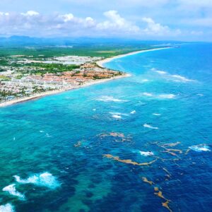 Drone view of coastal town located on lush forested shore washed by transparent azure sea in tropical country
